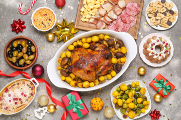 Christmas table setting with tasty chicken, pastries and gifts on dark background