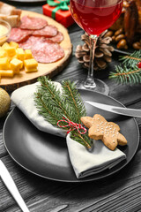 Christmas table setting with cookie and fir branches on black wooden background, closeup