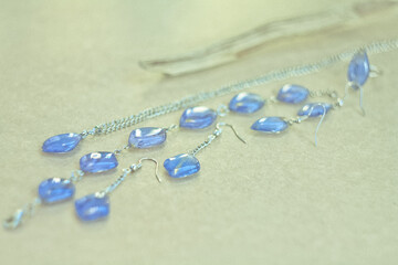 Close up craft bijouterie set with blue gems concept photo. Side view photography with plywood display on background. High quality picture for wallpaper, travel blog, magazine, article