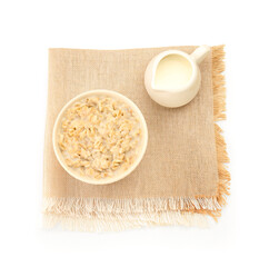 Bowl of tasty oatmeal, pitcher with milk and napkin isolated on white background