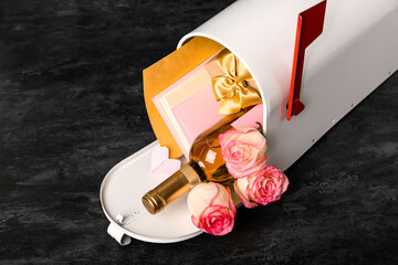 Mailbox with letters, bottle of wine, gift and roses on dark background. Valentine's Day celebration