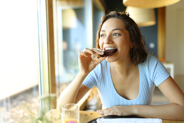 Happy woman eating chocolate cake in a restaurant