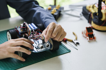 teenager students doing robot arm and robotic cars homework project in house assemble the circuit...