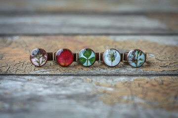 Close up handmade rings with flowers and leaves concept photo. Craft jewelry. Front view photography with old boards on background. High quality picture for wallpaper, travel blog, magazine, article
