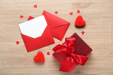 Blank letter, gift and hearts on wooden background. Valentine's Day celebration