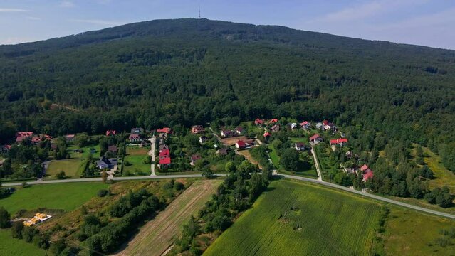 Mountain village and road with moving cars, aerial view. Beautiful mountain landscape with residential neighborhood and green fields. Countryside view