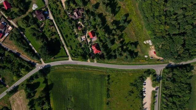Mountain village and road with moving cars, aerial view. Beautiful mountain landscape with residential neighborhood and green fields. Countryside view