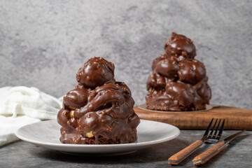 Chocolate cake on a dark background. Dessert with chocolate sprinkled on profiteroles grains. Bakery products