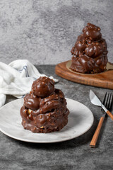 Chocolate cake on a dark background. Dessert with chocolate sprinkled on profiteroles grains. Bakery products