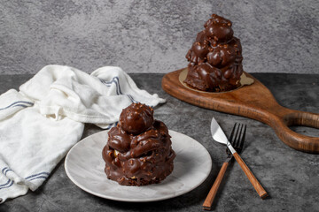 Chocolate cake on a dark background. Dessert with chocolate sprinkled on profiteroles grains. Bakery products
