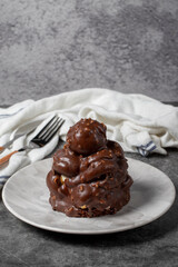 Chocolate cake on a dark background. Dessert with chocolate sprinkled on profiteroles grains. Bakery products