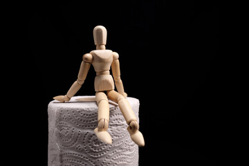 wooden figurine sits on a roll of toilet paper. Toilet, diarrhea concept