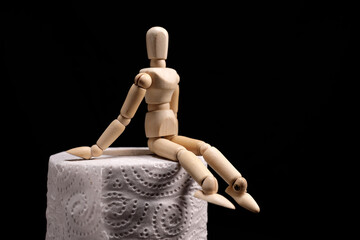 wooden figurine sits on a roll of toilet paper. Toilet, diarrhea concept
