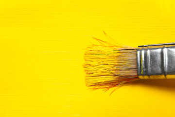 Paint brush with yellow paint and yellow paint background