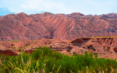 Natural unusual landscape of red rocks against the backdrop of blue mountains. The extraordinary beauty of nature is similar to the Martian landscape. Amazingly beautiful landscape.