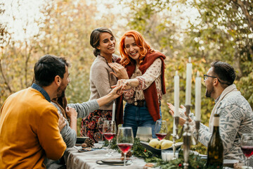 Lunch Party with a Crowd of Multiethnic Diverse Friends Celebrating. Beautiful Happy Female Hosts Propose an Engagement to their friends.