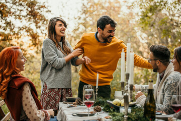 Excited young couple announcing their engagement during a gathering with their friends on an autumn lunch at the garden.