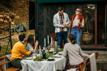 A blindfolded woman navigated by her husband is about to be surprised by a group of friends during a garden party.