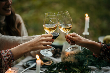 Smiling young woman toasting white wine with friends during an outdoor party. Young people enjoy at...