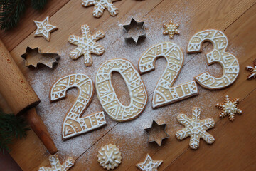 Gingerbread cookies with sugar glaze decoration in the form of numbers 2023 on wooden background....