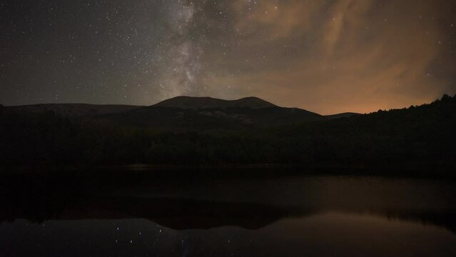 Night time lapse of the movement of the stars and the Milky Way over  the Moncayo mountain, with reflection in the lake. Zaragoza, Spain