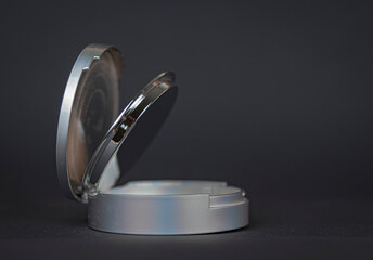 Powder in a round box of light gray color on a dark gray background