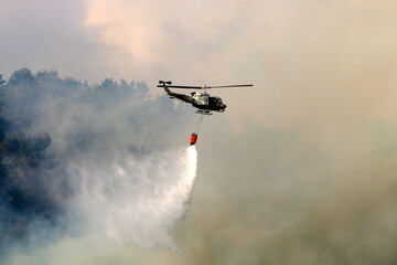 Naklejka na ściany i meble A helicopter puts out a forest fire in the mountains of northern Israel.