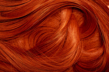Red hair close-up as a background. Women's long orange hair. Beautifully styled wavy shiny curls....