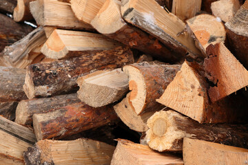 Natural wooden background - closeup of chopped firewood. Firewood prepared for winter Pile of wood logs. Chopped wood for fireplace heating, alternative to gas and electricity.