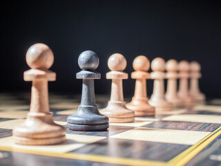 Black pawn standing in a row of white ones. Selective focus on the subject. The concept of...