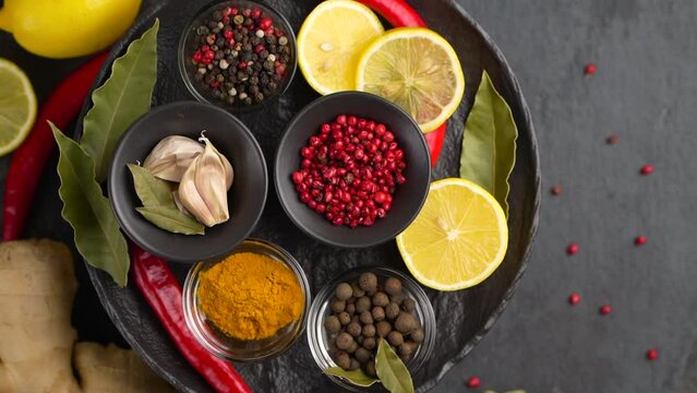Set of Spices and herbs for cooking. Small bowls with colorful seasonings and spices - basil, pepper, saffron, salt, paprika, turmeric. On black stone table top view copy space
