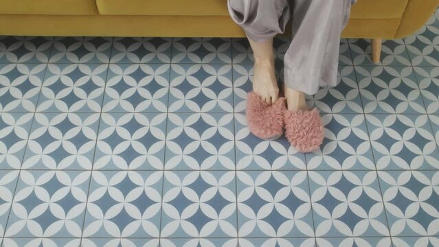 A Girl In Pajamas And Pink Slippers Puts Them On. View From Under The Bed.