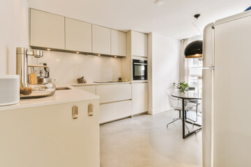 a kitchen and dining area in a modern apartment with white cabinetry, counters and appliances on...