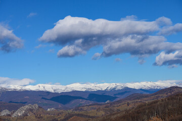 Fototapeta na wymiar Mountains, snow, clouds in the blue sky. Snow-covered mountains, valleys and hills. 