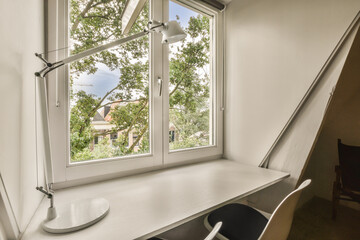 a desk and chair in front of a window looking out onto the street with trees on either side of it