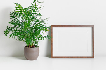 Blank landscape frame mockup in white room with green home plant