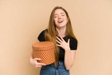 Young redhead woman holding a heart pattern gift for valentines day cut out isolated laughs out...