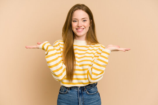 Young Redhead Woman Cut Out Isolated Makes Scale With Arms, Feels Happy And Confident.