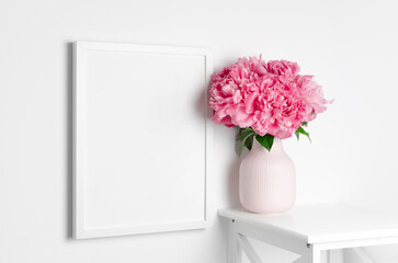 Frame mockup on white wall with peony flowers for artwork presentation
