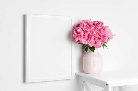 Frame mockup on white wall with peony flowers for artwork presentation