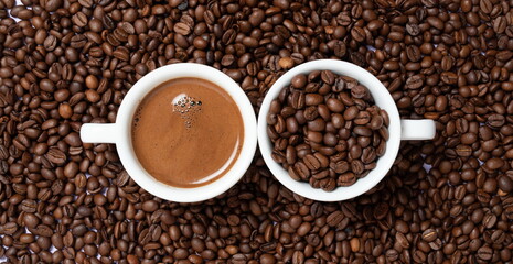 two cups of coffee on coffee beans on a brown background.