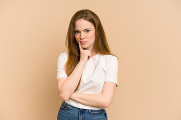 Young redhead woman cut out isolated looking sideways with doubtful and skeptical expression.