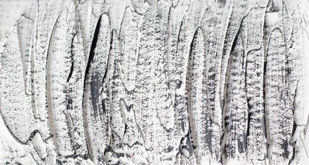 The rough texture of white putty and concrete with black brush stains. Copy space for text. Flat...