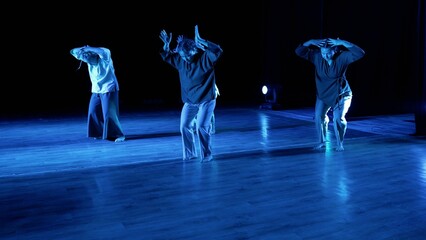 A group of dancers perform on stage. A group of artists are rehearsing on stage with lights and...