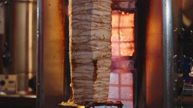 A large piece of chicken meat for shawarma. Street food. The juice flows down the meat. Fire.