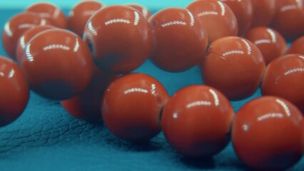 Close up macro shot of a red beads necklace on a blue background, 4K
