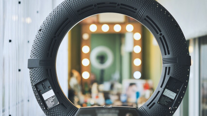 The makeup artist works in the office against a backdrop of circular lighting.