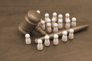 Many wooden people figures and broken judge gavel. Unfairness and injustice concept.