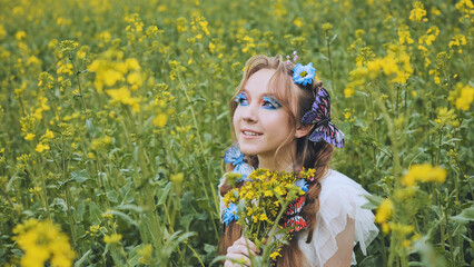 A young girl poses in a rapeseed field with a beautiful hairdo of flowers and butterflies.
