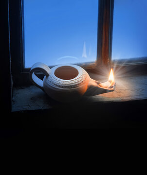 Clay oil lamp on the old window